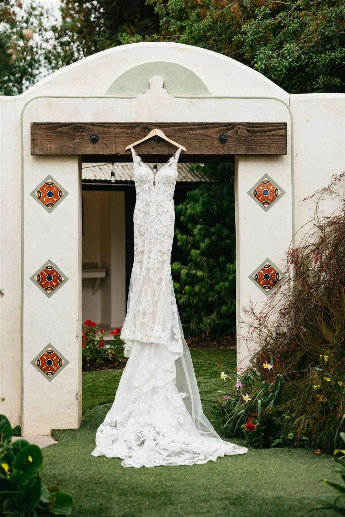 hacienda adobe wedding venue with tile decorated arch and hanging lace wedding dress