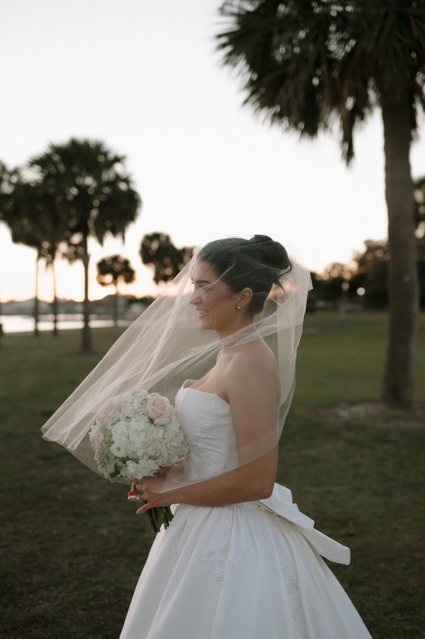 soft ivory face veil over bride holding round white and blush bouquet in California golf course
