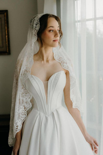 stunning deep v corset gown with lace mantilla wedding veil from one blushing bride