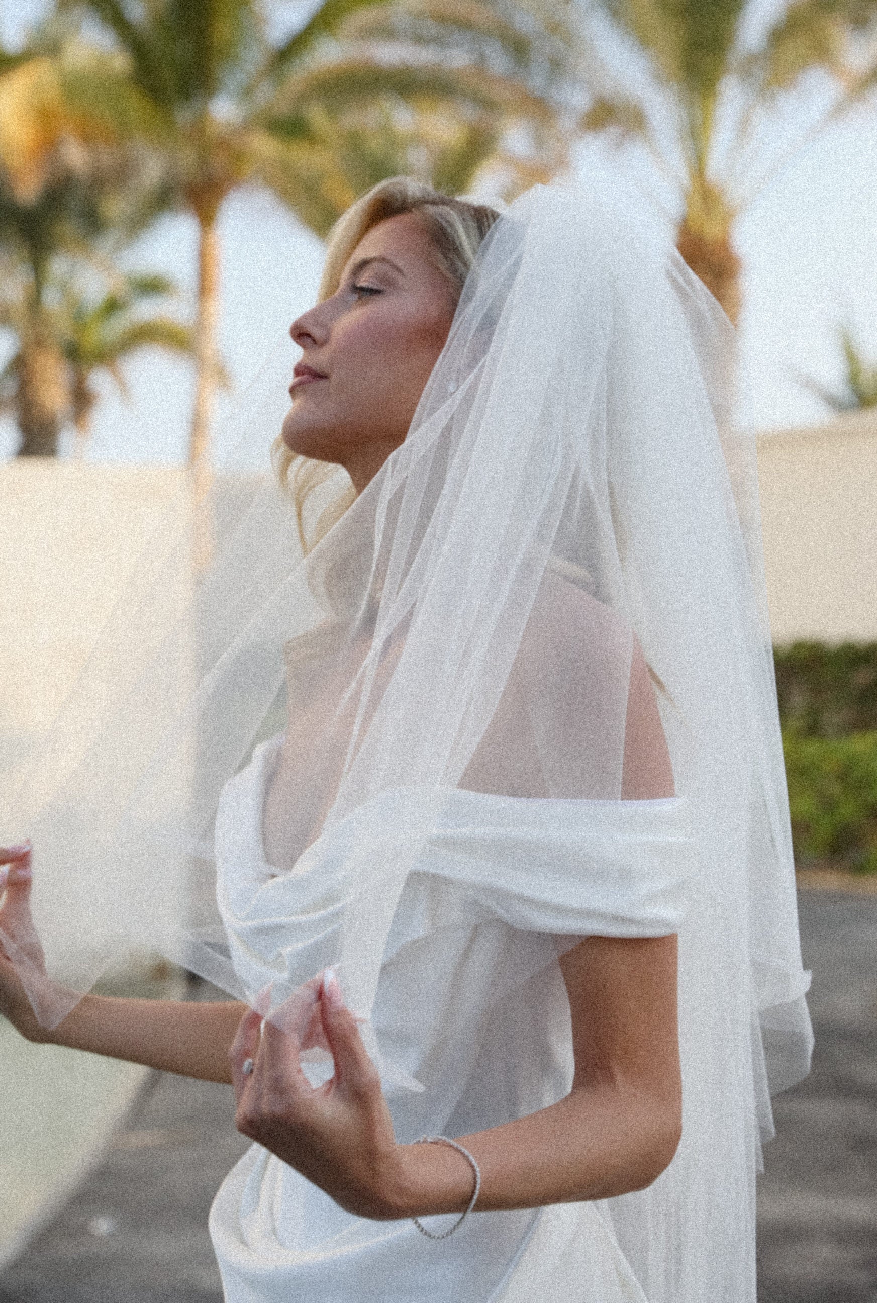 bride wearing an off white white wedding dress with a puffy 80s inspired veil in a tropical setting