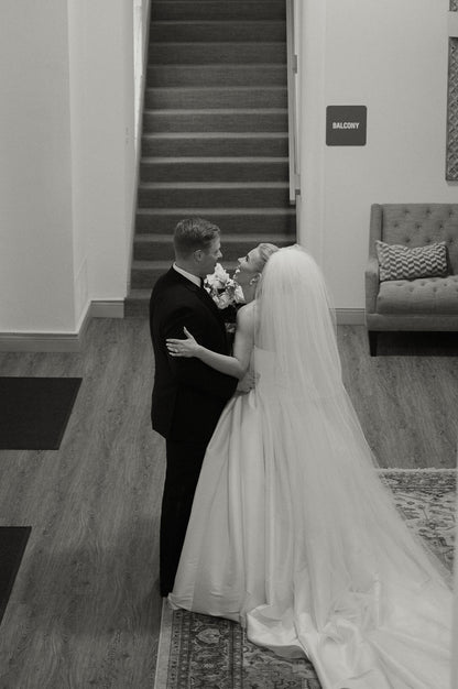 Black and white photo of a bride and groom with extra long puffy four layer wedding veil over updo