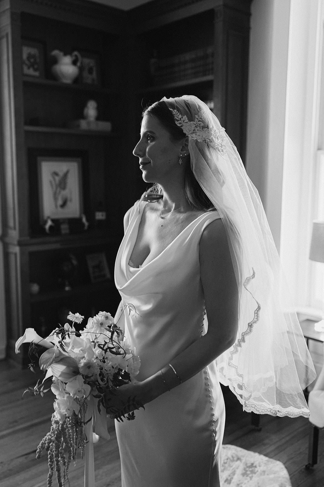 Black and white photo of a bride holding a bouquet wearing bespoke one of a kind vintage Juliet cap wedding veil
