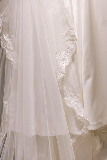 Close-up of an ivory lace wedding veil with tulle and French corded scallop lace trim