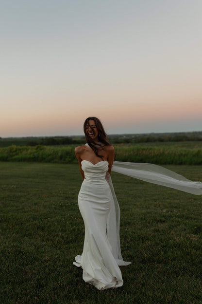 sunset wedding with rusched wedding dress and long cathedral length silk tulle wedding scarf blowing in wind