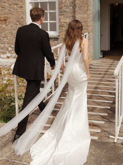 groom and bride in wedding long neck scarf in sheer tulle  walking up a stone staircase.