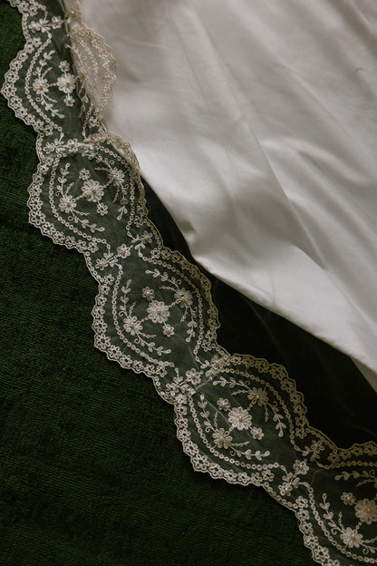 Close-up of intricate crochet pearl lace trim on a wedding veil made from mother of bride's vintage wedding gown