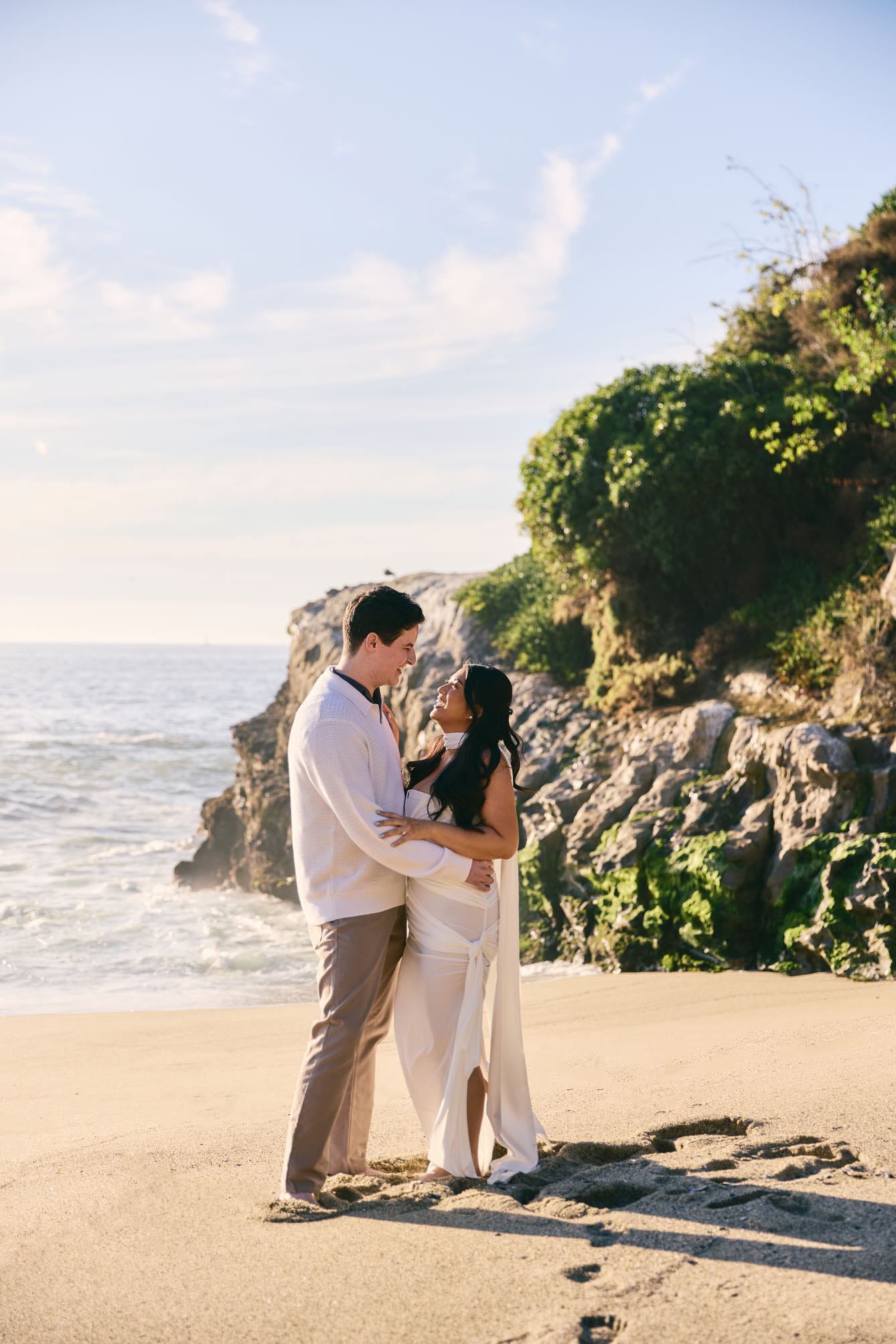 beach engagement photo shoot with goddess style white gown and long silk satin bridal gown