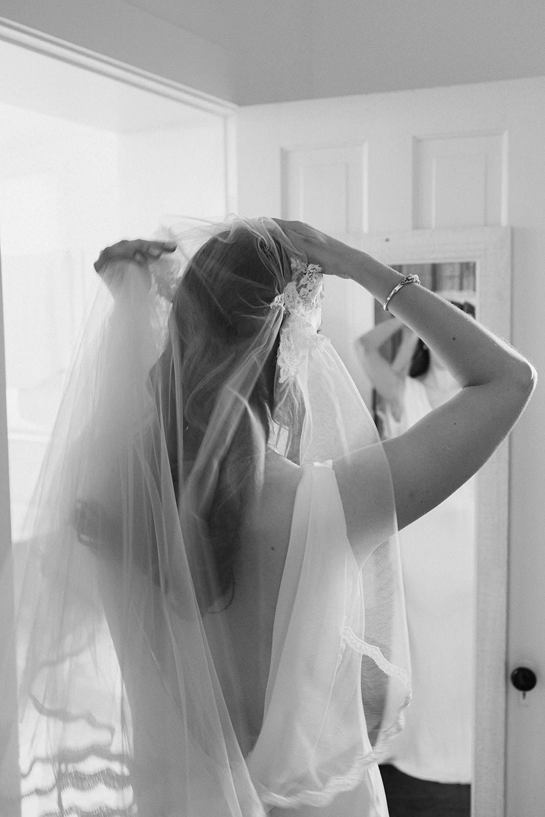 putting on Juliet cap fingertip length wedding veil in hair before ceremony