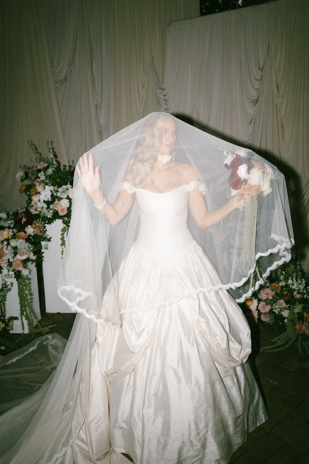 Bride in an ivory wedding dress with a drop lace blusher wedding veil from one blushing bride in California 