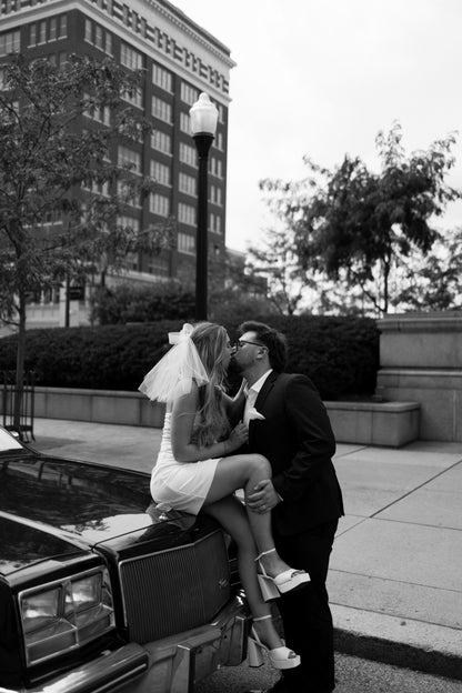 cute short wedding veil hair bow on bride wearing tall platform wedding shoes kissing fiance