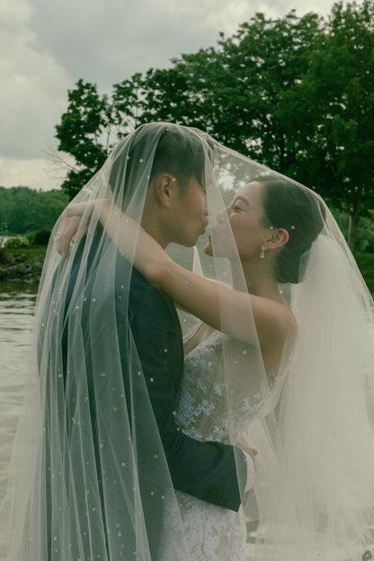 bride wearing dew drop wedding veil like Sofia Richie with blusher over her and fiancé