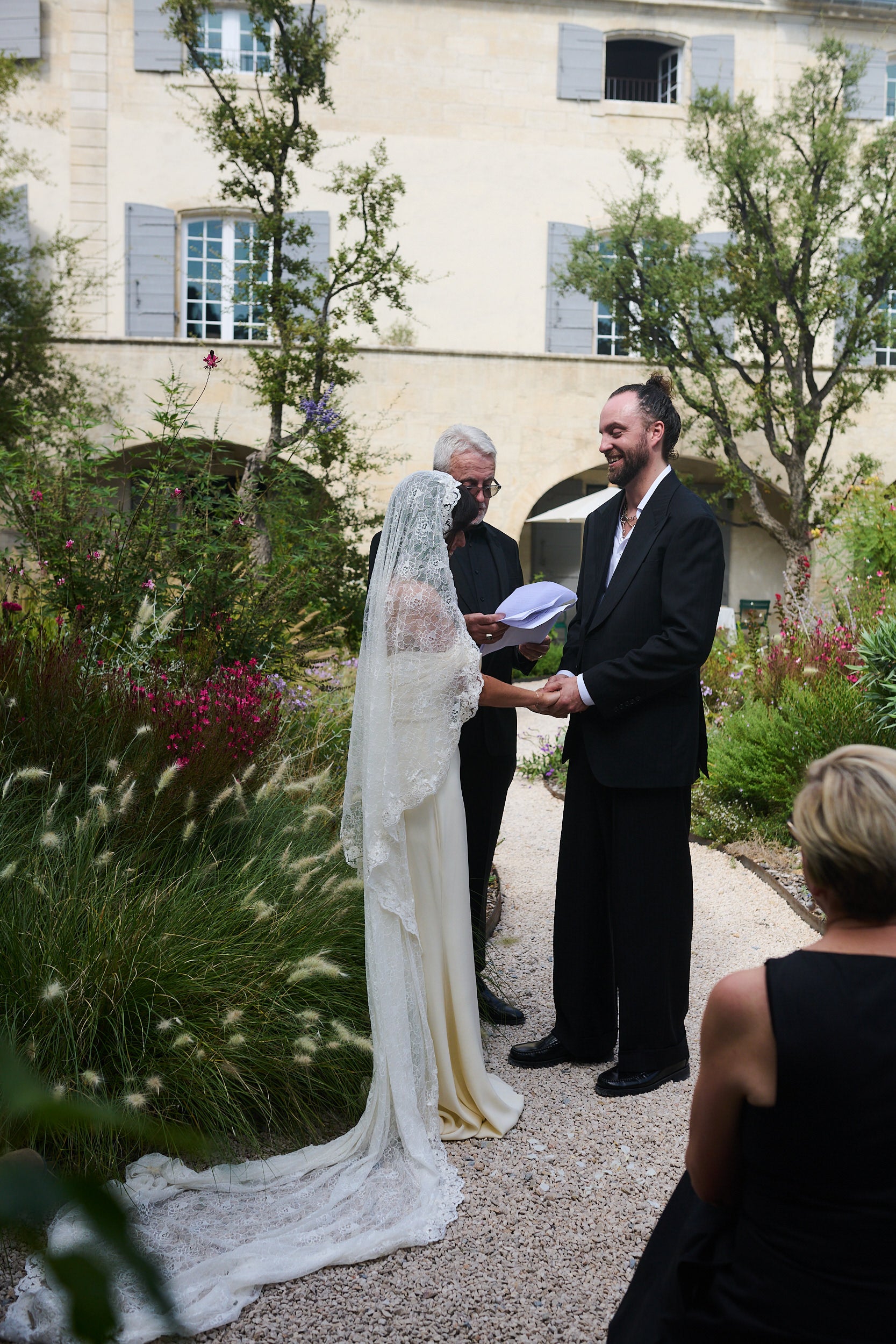 Wedding ceremony taking place outdoors in Italy villa with a bride in ivory long bridal veil with recycled lace materials and textiles