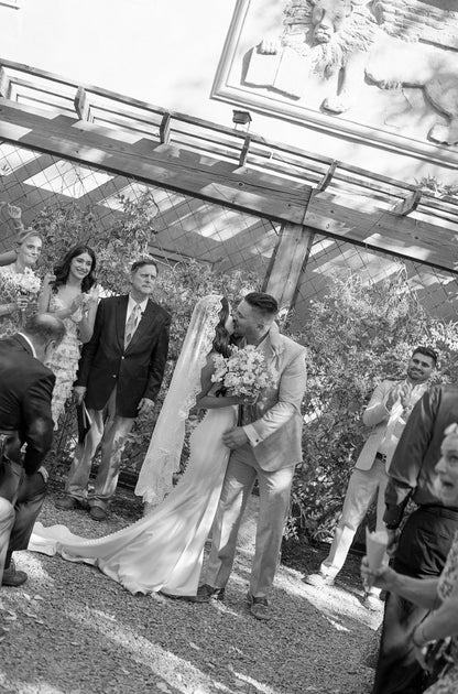 bride and groom kissing with bride wearing Chantilly lace trimmed mantilla on top of her downdo hairstyle