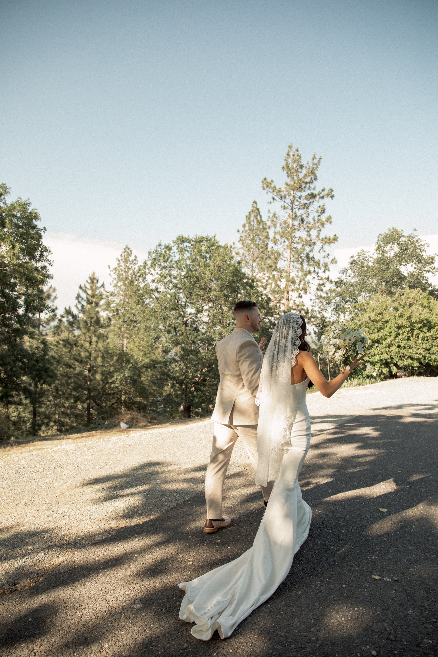 vintage inspired mantilla floral lace veil waltz length on bride walking with groom outside